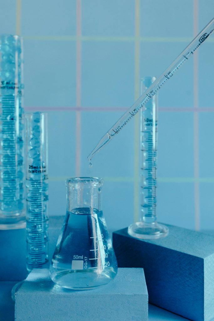 Collection of blue-toned glassware in a laboratory setting with pipette and graduated cylinders.